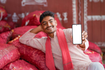young indian farmer showing smartphone screen