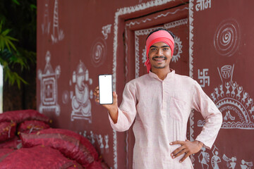 young indian farmer showing smartphone screen