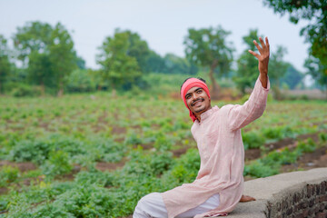 young indian farmer standing at green agricultural field