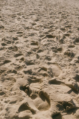 chain of footprints in the sand. The footprints of human shoes are arranged in a row and very close to each other, the beach is trampled by feet.