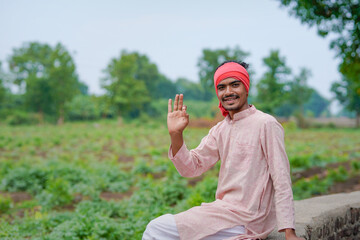 young indian farmer standing at green agricultural field