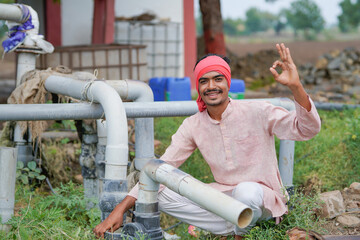 young indian farmer sitting at agricultural field