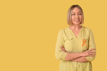 Happy mature woman with ribbon on yellow background. Multiple Sclerosis Awareness Month
