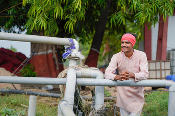 young indian farmer standing at agricultural field