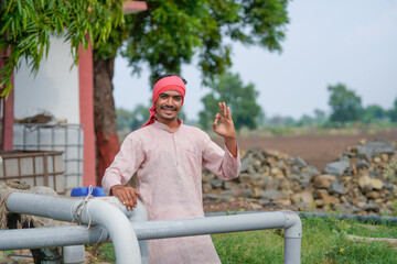 young indian farmer standing at agricultural field