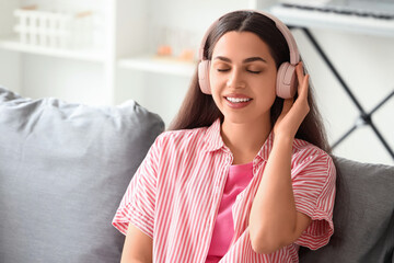 Beautiful young happy woman in headphones listening music at home