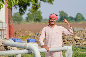 young indian farmer standing at agricultural field