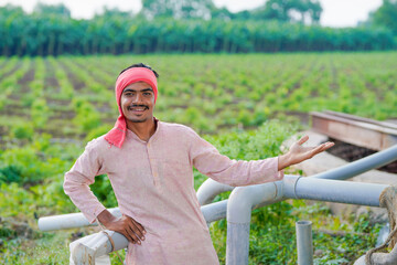 young indian farmer standing at agricultural field