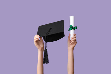 Female hands with graduation hat and diploma on lilac background