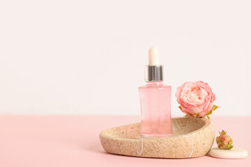 Bottle of cosmetic oil, roses and stone tray on pink background