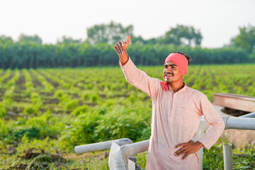 young indian farmer standing at green agricultural field