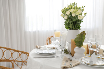 Beautiful table setting with eustoma flowers and candles for wedding celebration in room