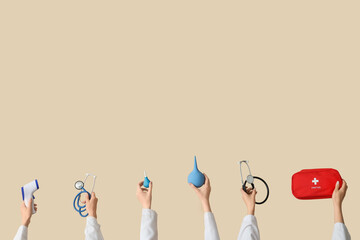 Female hands with thermometer, enemas, stethoscopes and first aid kit on beige background
