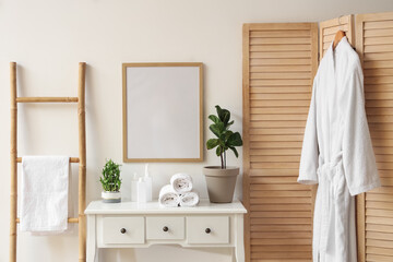 Interior of modern stylish bathroom with commode and hanging bathrobe