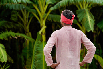 young indian farmer standing at banana field