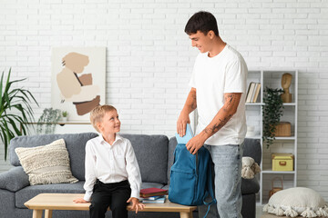 Father packing backpack with books for his little son at home