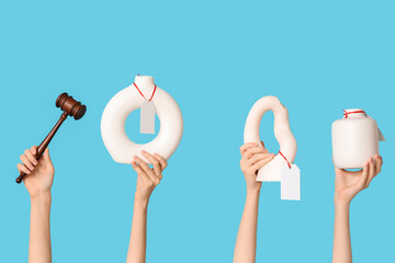 Female hands with auction gavel, wallet and antique vases on blue background