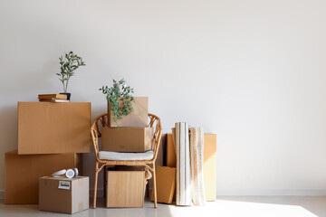 Armchair with cardboard boxes and things near light wall in room