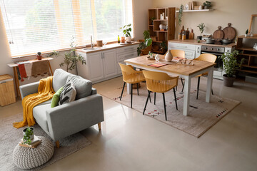 Cozy sofa, dining table and armchairs in interior of kitchen