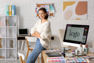 Young female graphic designer sitting on table in office