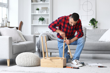 Fototapeta premium Young man assembling wooden table at home