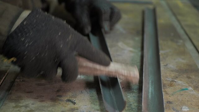 Workshop. A worker removes burrs from a sawn pipe that is on a workbench.
