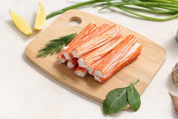 Wooden board with tasty crab sticks, dill and pieces of lemon on white background © Pixel-Shot