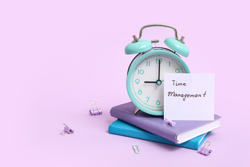 Paper sheet with text TIME MANAGEMENT, alarm clock, notebooks and stationery on lilac background