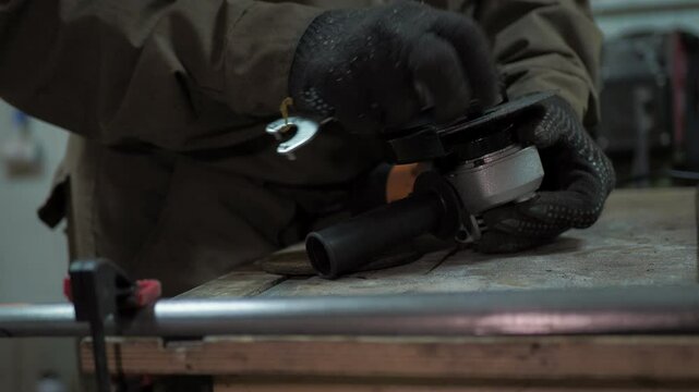 Workshop. A worker uses a special key to change the saw blade to a grinding blade on a angle grinder.