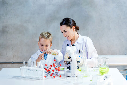 A young boy and a female scientist perform a science experiment together in a modern lab, symbolizing early eco-friendly farming education and hands-on STEM learning in sustainable innovation.