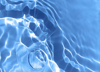 Abstract blurred shades of blue water background. Light and shadow ripples or splashes surface of water texture. Water waves and bubbles with shining and reflection pattern photography for​ artwork.