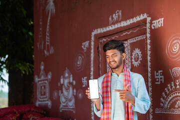 young indian farmer showing smartphone screen