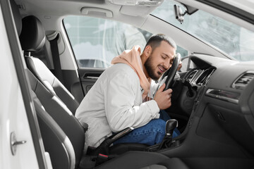 Handsome young man hugging steering wheel in car. I love my car concept