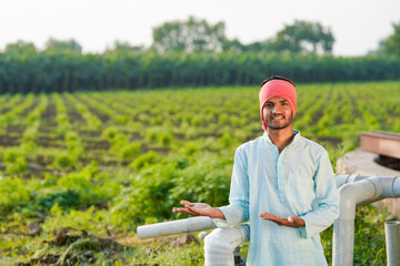 young indian farmer standing at agricultural field