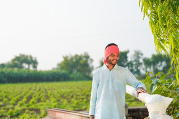 young indian farmer standing at agricultural field