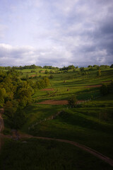 Idyllic countryside landscape with green rolling hills and dramatic sky.