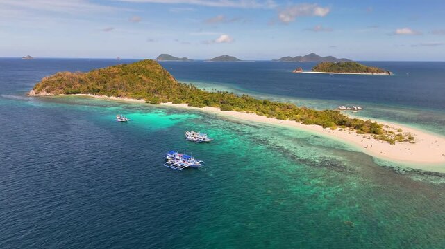 Aerial view of Manlihan Island in Linapacan, Philippines, featuring turquoise waters, white sand beach, boats, and lush vegetation surrounded by nearby islands under a sunny blue sky