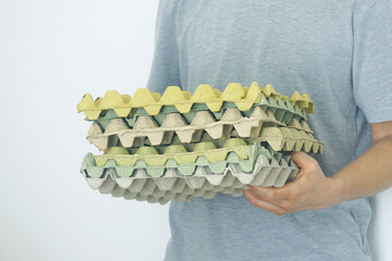 Daily sustainable habits: stack of multi-colored egg cartons held by man. Eco-conscious living and daily recycling efforts. Suitable for household responsibility and eco-friendly behavior illustration
