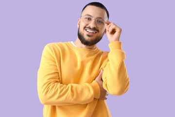 Handsome young man in eyeglasses on lilac background