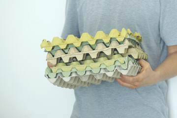 Man carrying multiple egg cartons for recycling, illustrating a personal approach to sustainability and conscious consumption. Ideal image for waste reduction and environmental responsibility topics