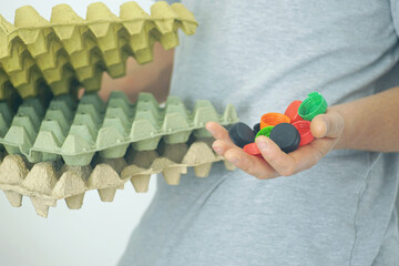 Close-up of hands sorting plastic caps and cardboard trays. Educational concept for environmental awareness, recycling practices, and waste reduction in schools, homes, and local communities.