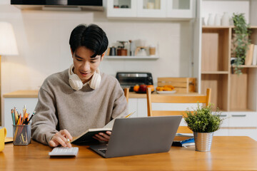 Man calculates expenses with laptop at home kitchen.