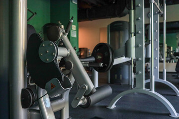 Close-up of leg curl machine beside Smith rack in an empty modern hotel gym, weights set for a strength workout