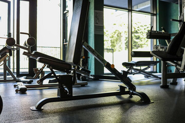 Adjustable weight bench sits in a sun-lit hotel gym; rubber flooring, nearby machines and...