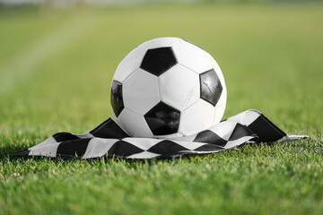 Soccer ball with finish flag on green stadium grass, closeup