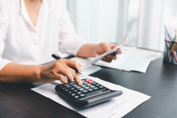 Using calculating machine, household carefully manages each bill and expense to plan financial...