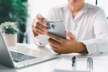 Close-up scene, a female seated at a table holds a smartphone, spending time on modern e-date...