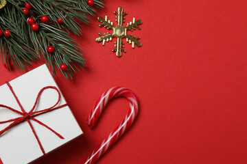 Top view of gift box trinket, fir branch, on red background, space for text