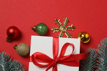 Top view of gift box trinket, fir branch, on red background, space for text