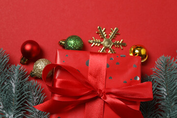 Top view of gift box trinket, fir branch, on red background, space for text